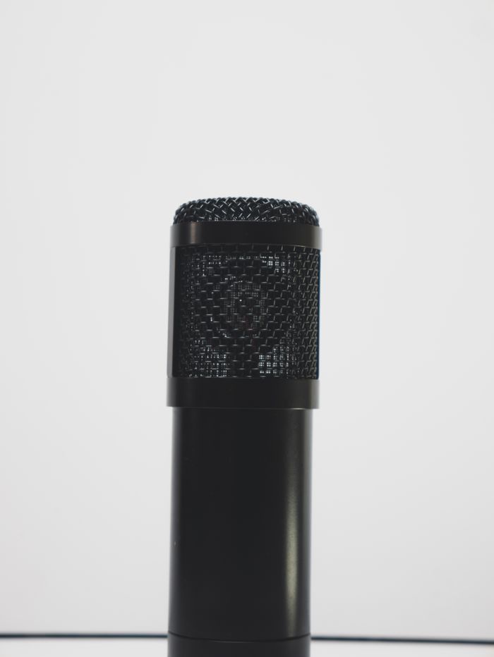 Gros plan d’un microphone noir sur fond blanc, idéal pour les thèmes liés à l’enregistrement audio.